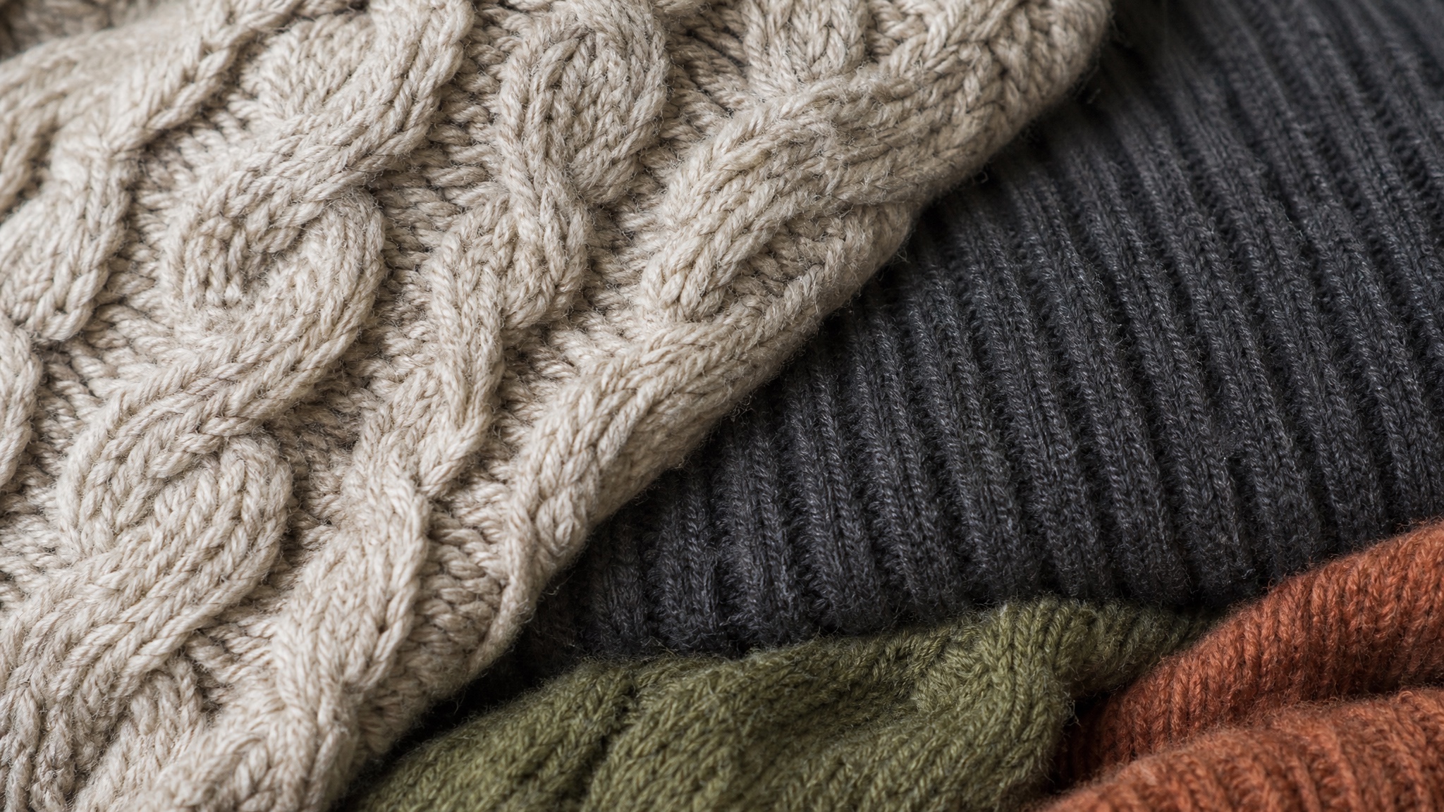 Close detail of overlapping charcoal ribbed and oatmeal cable knitted fabric